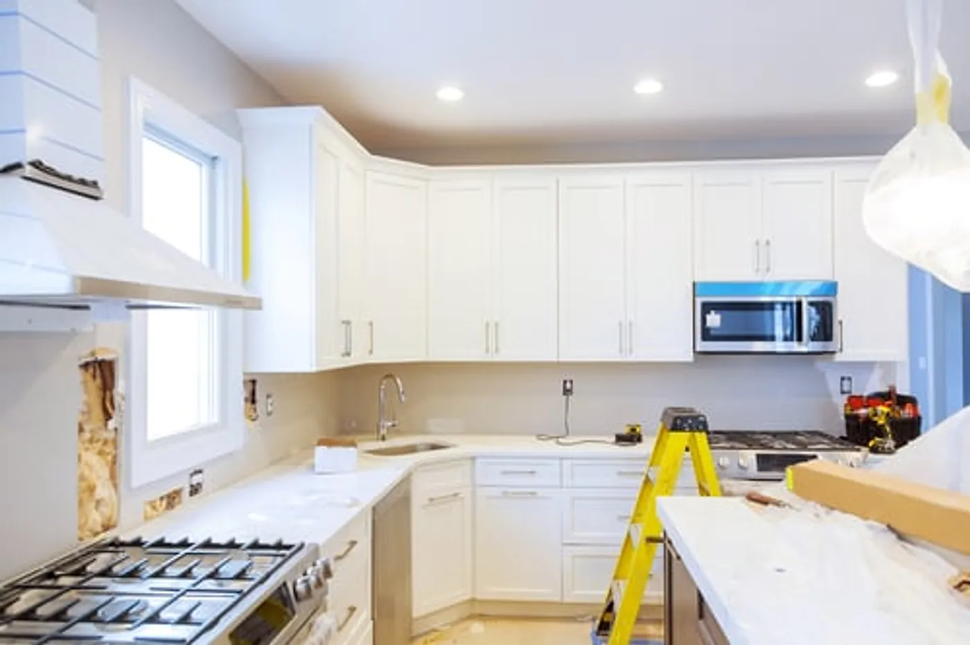 Bright white kitchen remodel nearing completion with new cabinetry and fixtures