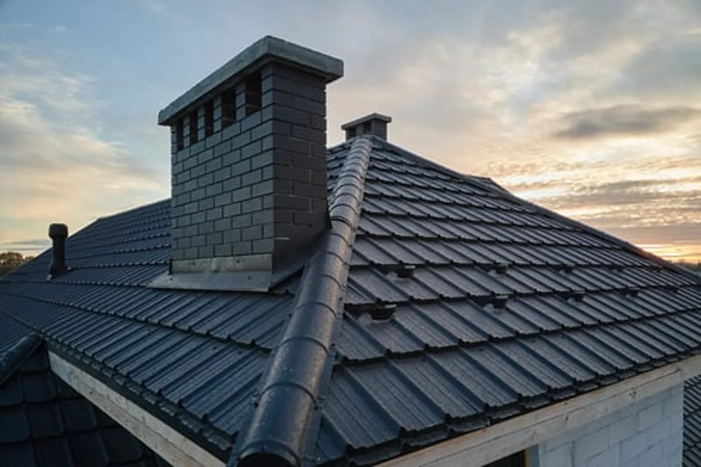 Finished architectural shingle roof with a brick chimney on a residential home at dusk