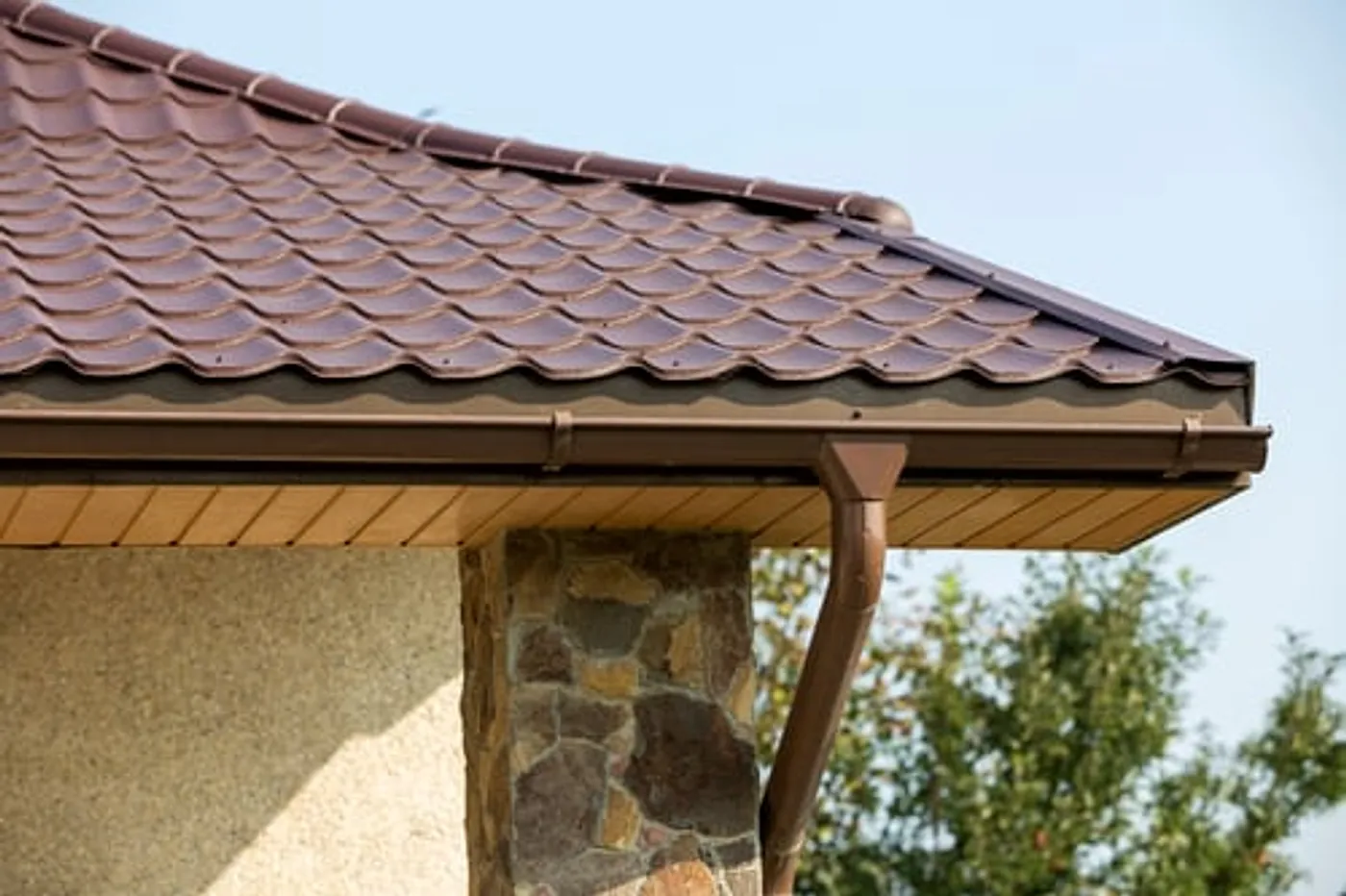 Newly installed seamless aluminium gutter and downspout along the roof edge of a Long Island home